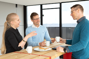 Tre kollegor fikar med kaffe och bullar på takterrassen på Midagons Örebrokontor.